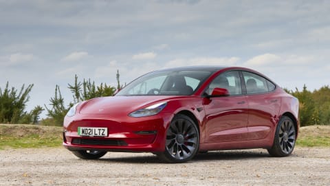 Red Tesla Model 3 parked in the countryside